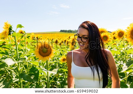 Happy attractive woman in sunflower field on a sunny day