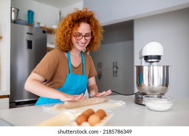 Happy attractive young adult woman housewife baker wear apron holding pin rolling dough on kitchen table baking pastry concept cooking cake biscuit doing bakery making homemade pizza at home - Shutterstock ID 2185786349