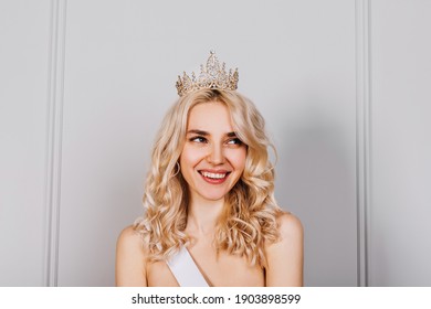 Happy Attractive Young Blonde Woman Wearing A Diamond Golden Crown And A White Ribbon, Smiling. Beauty Contest Winner Concept.