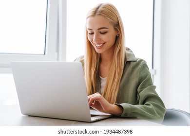 Happy Attractive Young Blonde Woman Sitting At The Table With Laptop Computer Indoors