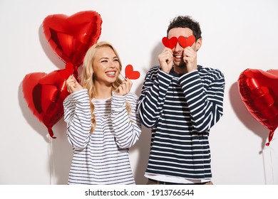 Happy Attractive Young Couple Celebrating Valentines Day With Red Heart Shaped Balloons Isolated Over White Background