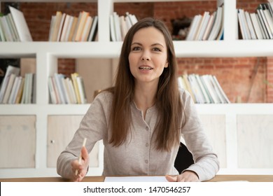 Happy attractive young hr manager sitting at table, holding video call job interview with potential employee. Smiling millennial female professional recording educational video for online course.