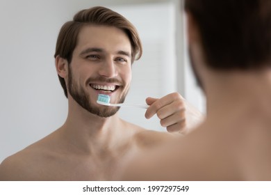 Happy Attractive Young Man Brushing Healthy Teeth In Bathroom, Holding Toothbrush With Mint Paste, Mineral Cleansing Gel, Enjoying Morning Mouth Hygiene For Fresh Breath, Dental Health Protection