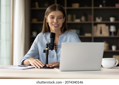 Happy Attractive Young Professional Female Blogger Talking In Stand Microphone, Voice Acting Or Recording Video, Looking At Laptop Screen, Communicating In Social Network Or Vlogging Online.