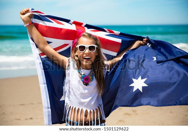 青い空と海の背景に羽ばたく青い白い赤いオーストラリアの国旗を持つ 幸せなオーストラリアの女の子 の写真素材 今すぐ編集