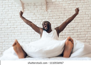 Happy awakened man is stretched out in bed. Early morning. Pleasant awakening. Waking up.