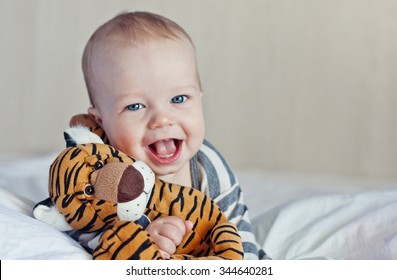 Happy Baby In Bed With A Favorite Toy