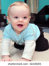 Happy Baby Boy With Blonde Hair And Blue Eyes Crawls On Floor With Huge Grin On His Cute Little Face