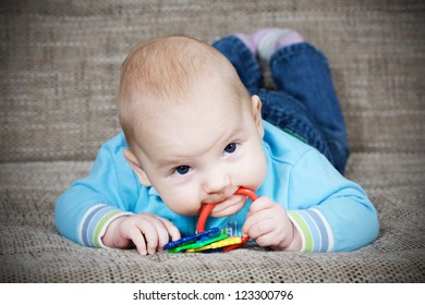 Happy Baby Boy Lying On His Stomach And Chew Toy.