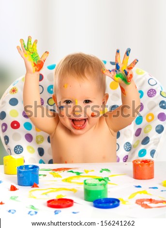 happy baby child draws with colored paints hands