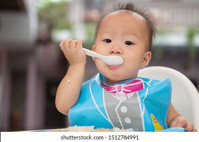 Happy Baby Child Sitting In Chair With A Spoon.Children Eat By Themselves.