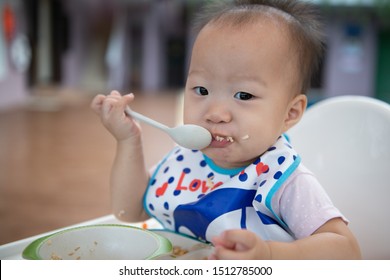 Happy Baby Child Sitting In Chair With A Spoon.Children Eat By Themselves.