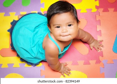 Happy Baby Girl Crawling On A Colorful Play Mat