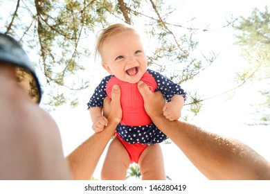 Happy Baby Girl In Her Prink And Blue Bathers In Her Fathers Arms