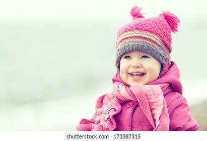 Happy Baby Girl In A Pink Hat And Scarf Laughs