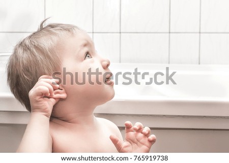 Happy baby girl preparing to bathe in the tub.