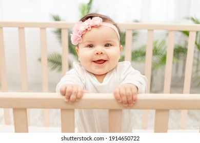 Happy Baby Girl Six Months Standing In The Crib
