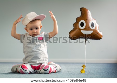 happy baby girl toddler plays in room with toy hat funny smile laugh blue carpet balloon poo emoji emoticon  