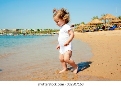 Happy baby is going to swim in the sea. Summer holidays at the beach.