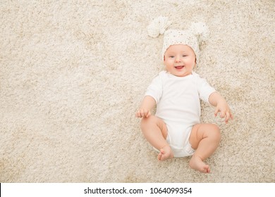 Happy Baby in Hat and Diaper Lying on Carpet Background, Smiling Infant Kid Boy in White Clothing, Child Six Months Old