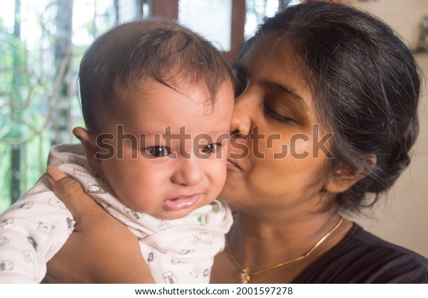 Happy Baby Loves mom Kisses. Loving Mother\
kissing cute little adorable kid on her lap. Close-up portrait.\
Indian ethnicity. Front view. Happy parents day Motherhood\
parenthood togetherness\
background