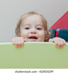 Happy Baby Playing Peek A Boo Behind Green Wall. Wall Can Be Used For Your Text Or Sign. Toddler Looking Straight To The Camera. 