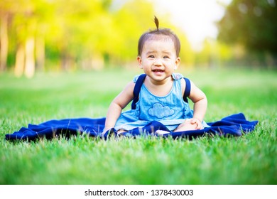 Happy baby sitting on the grass field laughing happily