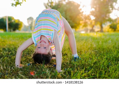 Happy baby standing upside down on green grass in summer Park. The concept of a healthy lifestyle. The fun and carefree childhood