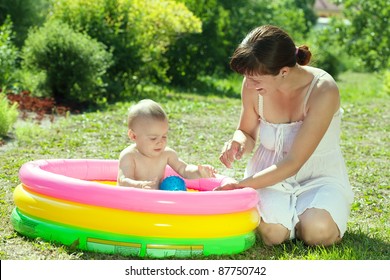 Happy Baby Swimming  In Kid Inflatable Pool With Mother