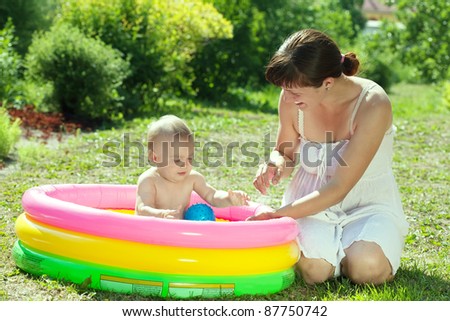 Happy baby swimming  in kid inflatable pool with mother