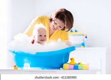 Happy Baby Taking A Bath Playing With Foam Bubbles. Mother Washing Little Boy. Young Child In A Bathtub. Smiling Kids In Bathroom With Toy Duck. Mom Bathing Infant. Parent And Kid Play With Water.