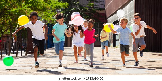 Happy with balloons run on the summer city street. High quality photo