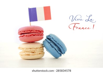 Happy Bastille Day Red, White And Blue Macarons With French Flag On White Wood Table With Vive La France Sample Text.