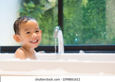Happy bath time, Asian boy take a bath in white bathtub. Adorable little boy smiling while take a bath in beautiful bathroom. Concept for healthcare and daily routine.