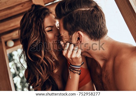 Happy to be in love. Beautiful young couple sitting face to face and smiling while resting in the beach hut