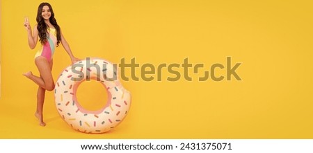 happy beach kid in swimsuit with doughnut inflatable ring on yellow background. Banner of summer child girl in swimsuit, studio poster header with copy space.