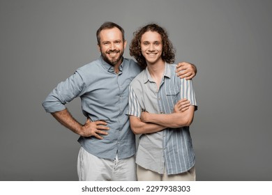 happy bearded father hugging shoulder of positive teenage son isolated on grey - Powered by Shutterstock