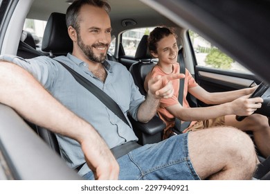 happy bearded father pointing with finger while showing direction to teenage son driving car - Powered by Shutterstock