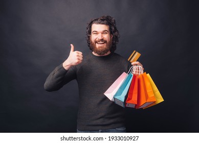 Happy Bearded Hipster Man Showing Thumb Up And Holding Shopping Bags And Credit Card.