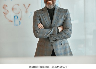 Happy bearded man in a jacket standing in front of wall with whiteboard, copy space