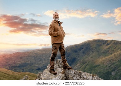 Happy Bearded Man reaching the destination and on the top of mountain at sunset on autumn day Travel Lifestyle concept The national park Lake District in England