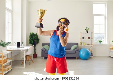 Happy bearded sport contest winner showing off his awards and trophies. Crazy, goofy, funny champion holding golden cup and biting his medal to check if it's fake or a real one