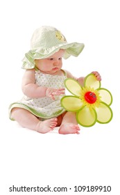 Happy Beautiful 6 Month Old Baby Girl In Green Seersucker Sun Hat And Sun Dress Sits And Plays With A Big Yellow Toy Daisy. Pastels, Isolated On White Background, Vertical, Copy Space.