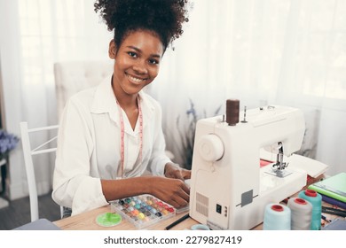 Happy beautiful African American woman fashion designer clothes working with sewing in own dressmaking studio or boutique	