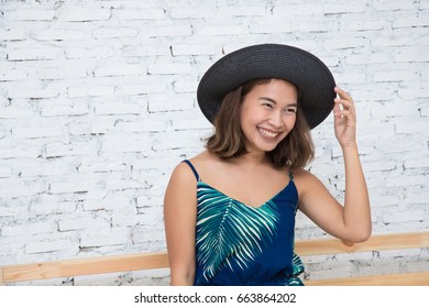 Happy beautiful Asian girl with cute smile touch her black floppy hat. Summer time concept with copy space.