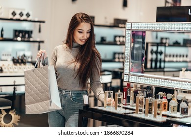 Happy beautiful Asian girl smiling young girl buys perfume cosmetics in the store