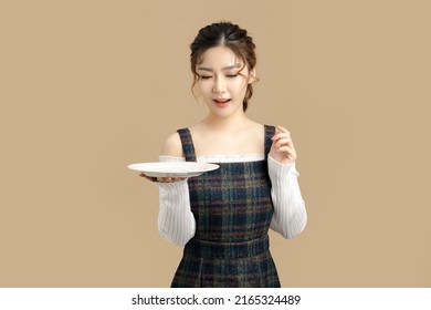 Happy Beautiful Asian Model Holding A Plate With Copy Space For Separate Products On Beige Background.