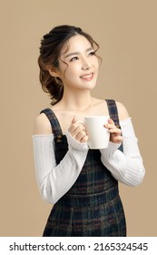 Happy Beautiful Asian Model Holding A Coffee Cup With Copy Space For Separate Products On Beige Background.