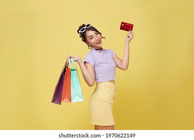 Happy Beautiful Asian Teen Shopaholic Women Holding Credit Card And Shopping Bags Isolated On Yellow Background.