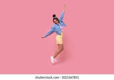 Happy Beautiful Asian Teen Woman In Yellow Glasses Listening Music In Headphones And Dance On Pink Background.	